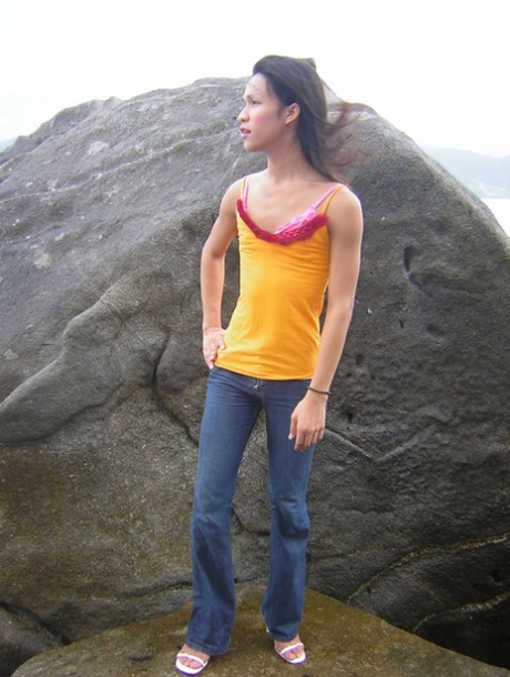 Lovely Thai shemale strips and masturbates while standing on a rock