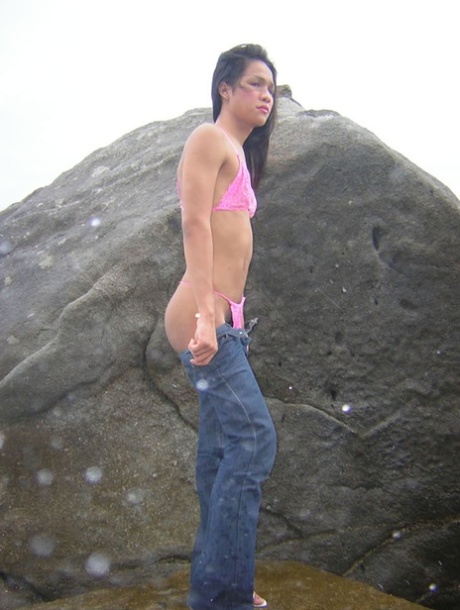 Lovely Thai shemale strips and masturbates while standing on a rock